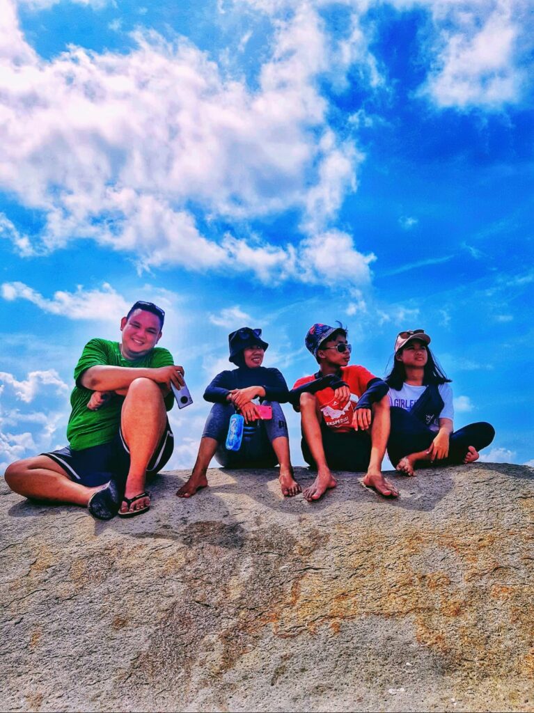 "Sebuah Keluarga Yang Sangat Kompak Saat Liburan Di Negri Laskar Pelangi Mereka Sedang Mengabadikan Foto Family Bersama-Sama Diatas Sebuah Batu Granit Raksasa, Sambil Duduk Bersantai Dengan Latar Belakang Langit Biru Yang Sangat Cerah. Dalam Perjalanan Paket Tour keluarga Belitung 4D3N Private Wisata Tour Belitung"