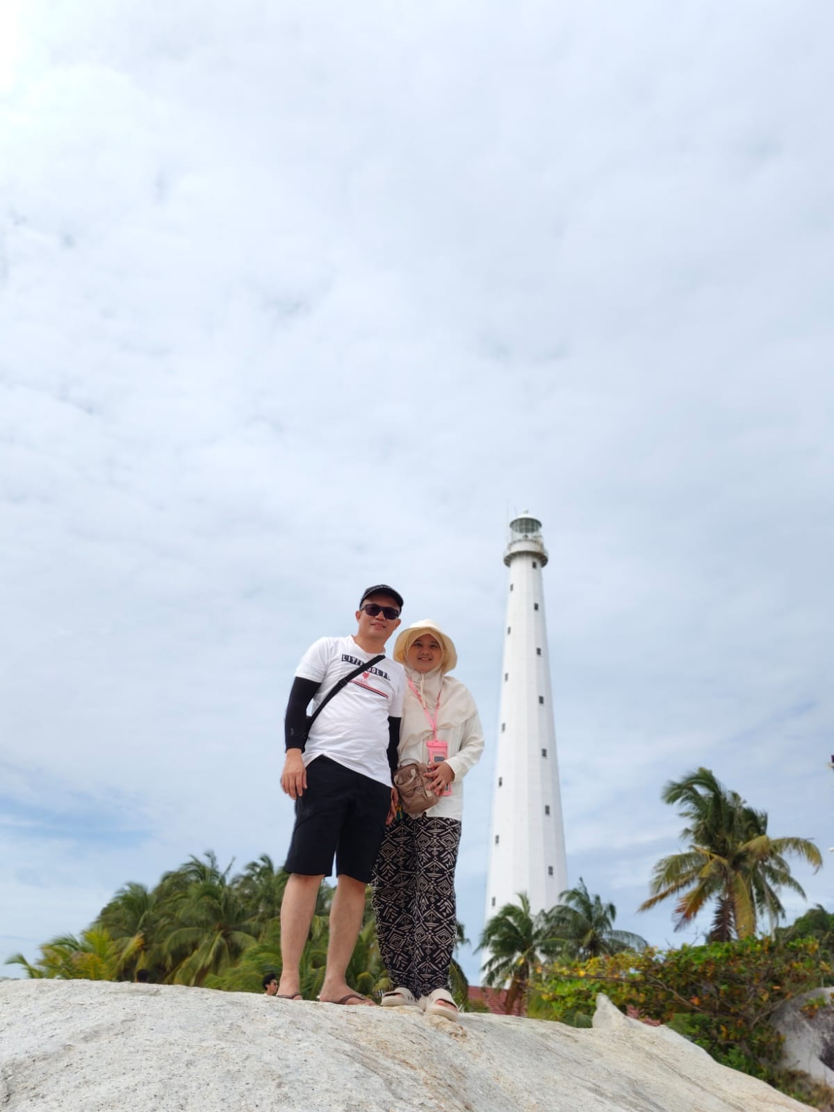 2 orang pasangan sedang honeymoon di belitung, yang berdiri di atas batu