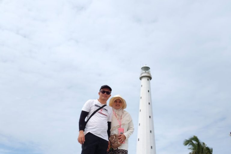 2 orang pasangan sedang honeymoon di belitung, yang berdiri di atas batu